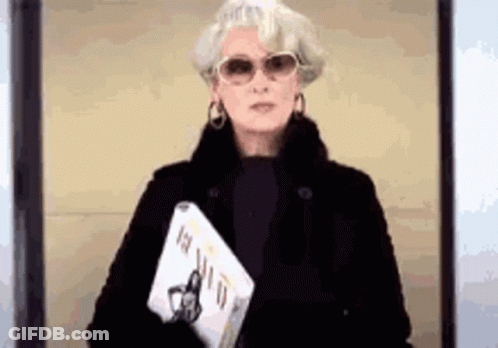 Woman In Sunglasses And Black Coat Holding Book And Laptop GIF