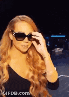 Woman In Sunglasses And Black Top Standing In Dark GIF
