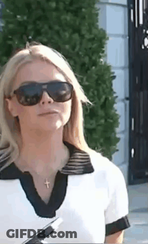 Woman In Sunglasses And Cross Necklace In Front Of Building GIF