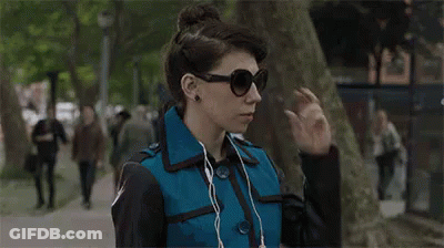 Woman In Sunglasses And Earbuds Walking GIF