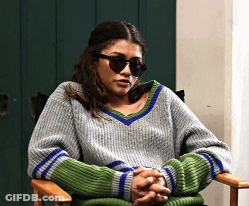Woman In Sunglasses And Grey Green Sweater Sitting GIF