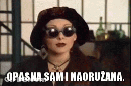Woman In Sunglasses And Hat Saying Opasna Sam I Naoruzana GIF