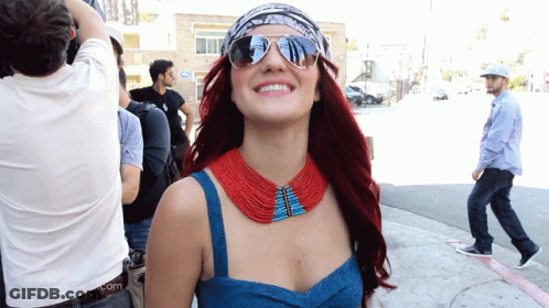 Woman In Sunglasses And Red Blue Necklace Smiling GIF