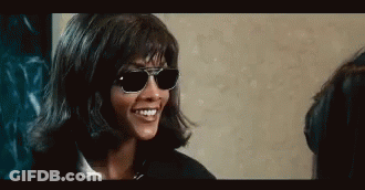 Woman In Sunglasses And Wig Smiling Talking To Another Woman GIF