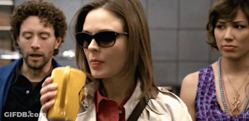 Woman In Sunglasses Holding Yellow Object GIF