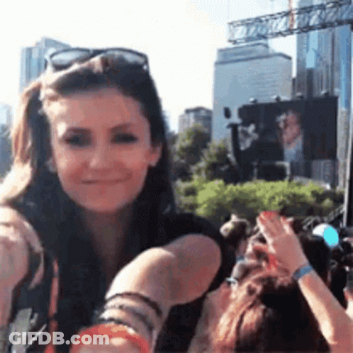 Woman In Sunglasses Smiling In Front Of Crowd GIF