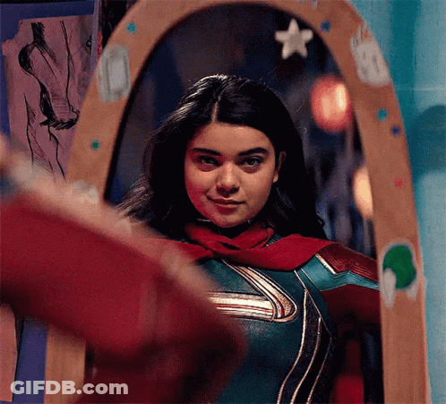 Woman In Superhero Costume Standing In Front Of Mirror GIF