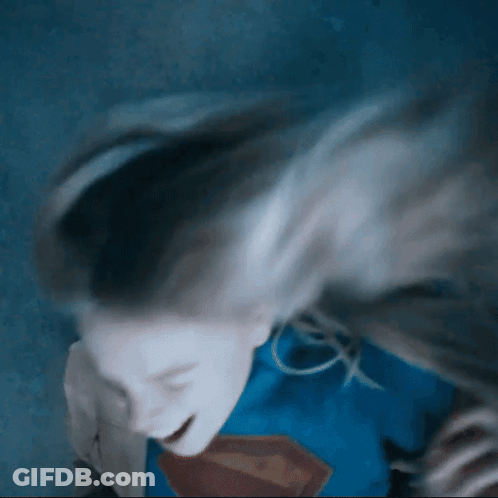 Woman In Superman Costume Laying Down Hair Blowing GIF