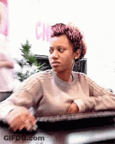 Woman In Sweater At Desk Looking At Camera GIF