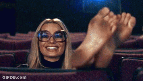 Woman In Theater With Feet Up Smiling GIF