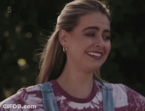 Woman In Tie Dye Shirt And Overalls Smiling With Number 5 GIF