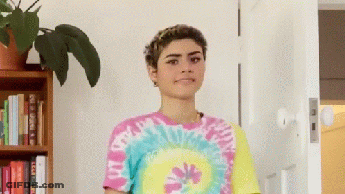 Woman In Tie Dye Shirt Standing In Front Of Door GIF