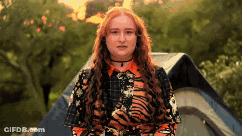 Woman In Tiger Print Shirt In Front Of Tent GIF