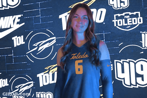 Woman In Toledo 6 Jersey In Front Of Logo Wall GIF