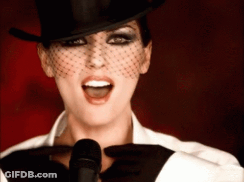 Woman In Top Hat And Veil Singing Into Microphone GIF