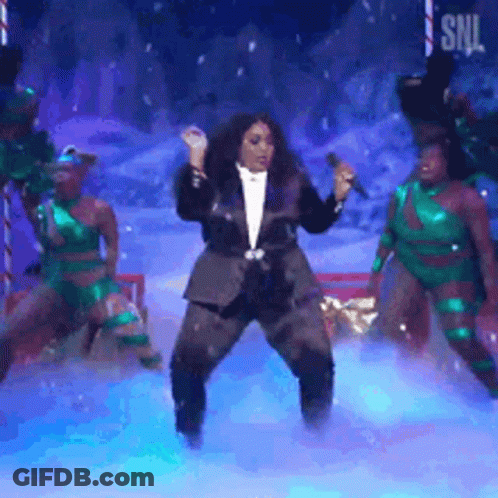 Woman In Tuxedo Singing Into Microphone Surrounded By Dancers GIF