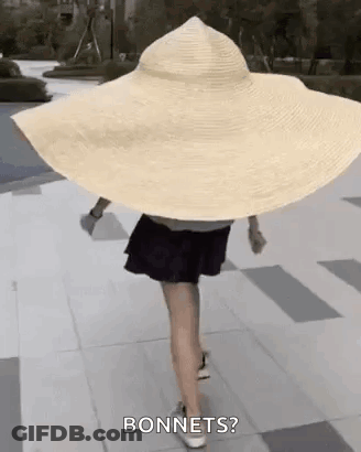 Woman In Very Large Hat Walking Down Sidewalk GIF