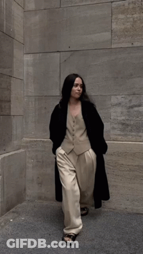 Woman In Vest And Pants Walking On Sidewalk GIF