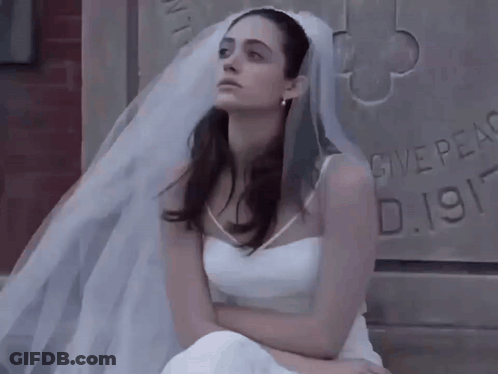 Woman In Wedding Dress Sitting In Front Of Stone Wall Saying Give Peace GIF