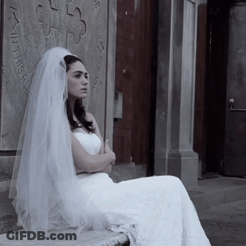 Woman In Wedding Dress Sitting In Front Of Wall Saying In This GIF