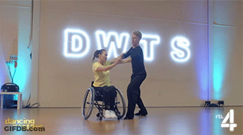 Woman In Wheelchair Dancing With Man In Front Of DWTS Sign GIF