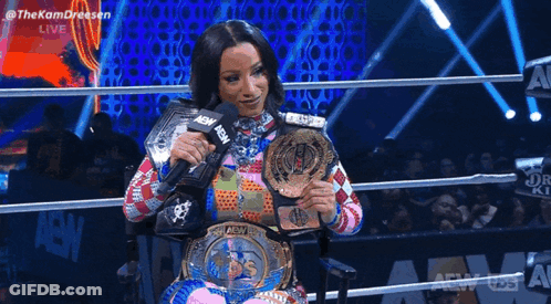 Woman In Wheelchair Holding Wrestling Belt And Microphone GIF