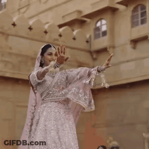 Woman In White And Silver Dress Dancing In Front Of Building GIF