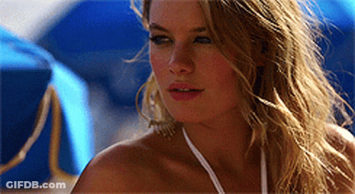 Woman In White Bikini Standing Before Blue Umbrellas GIF