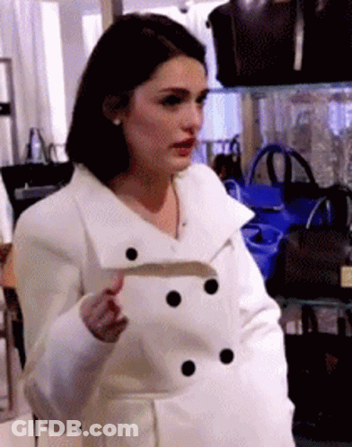 Woman In White Coat In Front Of Handbags GIF