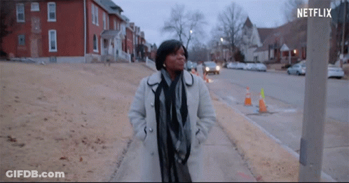 Woman In White Coat Walking Down Sidewalk With Netflix Logo GIF