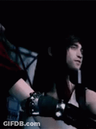 Woman In White Dress And Red Jacket Standing Next To Man In Dark Room GIF