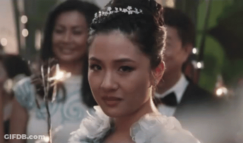 Woman In White Dress And Tiara In Front Of Group GIF