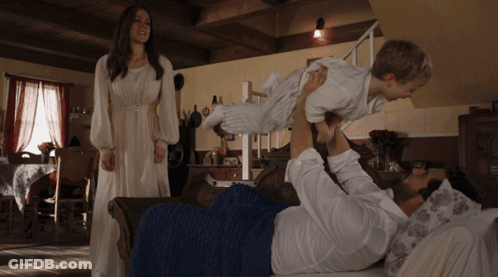 Woman In White Dress Behind Man Holding Child GIF