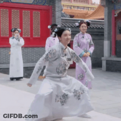 Woman In White Dress Dancing In Front Of Women In Purple Dresses GIF