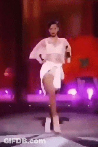 Woman In White Dress Dancing On Stage With Purple Lights GIF