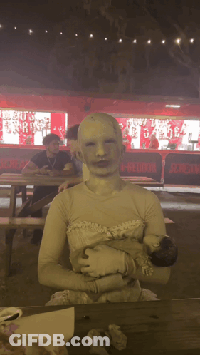 Woman In White Dress Holding Baby Beside Scream Sign GIF