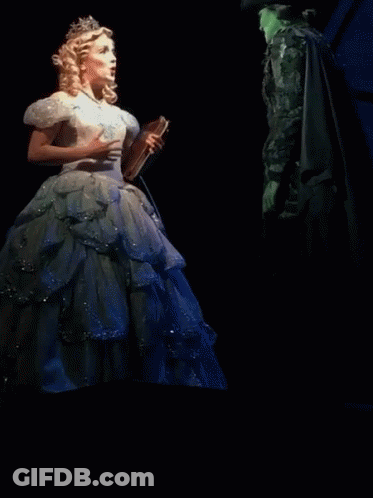 Woman In White Dress Holding Book Next To Green Woman GIF