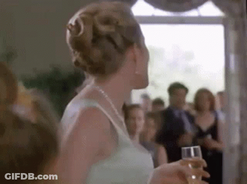 Woman In White Dress Holding Champagne Before Crowd GIF