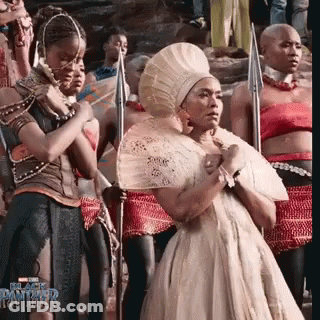 Woman In White Dress Holding Fan With Spear Holders GIF