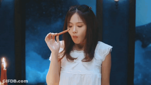 Woman In White Dress Holding Pencil To Mouth GIF