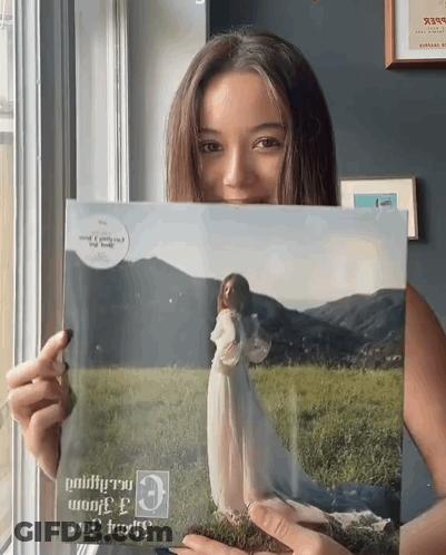 Woman In White Dress Holding Picture Of Herself GIF