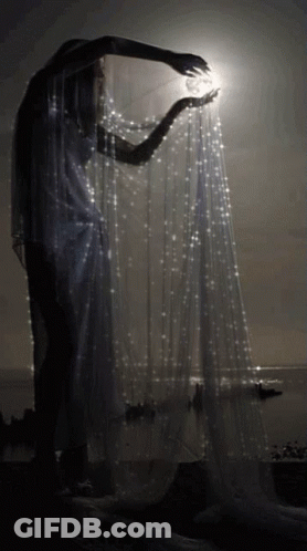 Woman In White Dress Holding White Cloth In Dark GIF