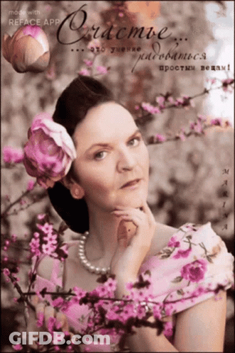 Woman In White Dress In Front Of Flower Wall GIF