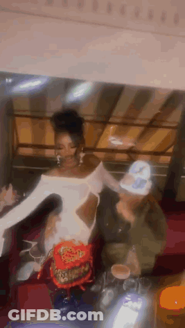 Woman In White Dress Next To Man In Green Jacket GIF