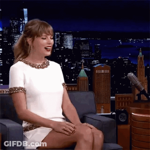 Woman In White Dress Sitting Cross-Legged And Laughing GIF