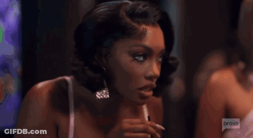 Woman In White Dress Sitting In Front Of Bravo Logo GIF