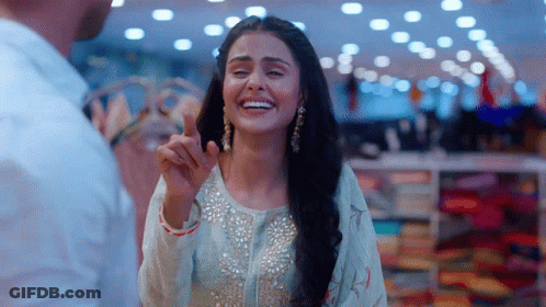Woman In White Dress Smiling And Pointing At Man GIF