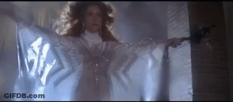 Woman In White Dress Standing In Front Of Door With Cloth Covering Her GIF