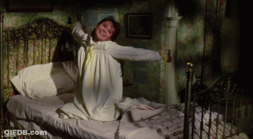 Woman In White Dress Stretching On Bed GIF