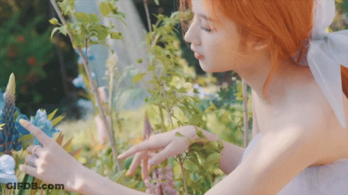 Woman In White Dress Touching Blue Flower GIF